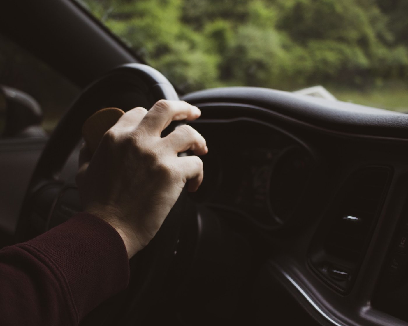 Driver's hand on the steering wheel on an open road