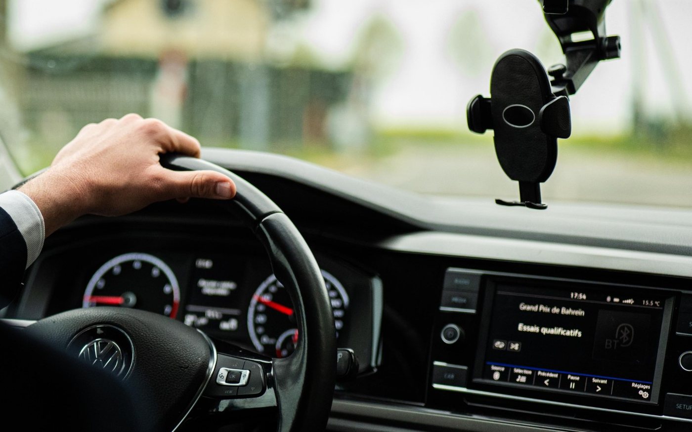 Driver's hand on the steering wheel, road ahead through the windscreen
